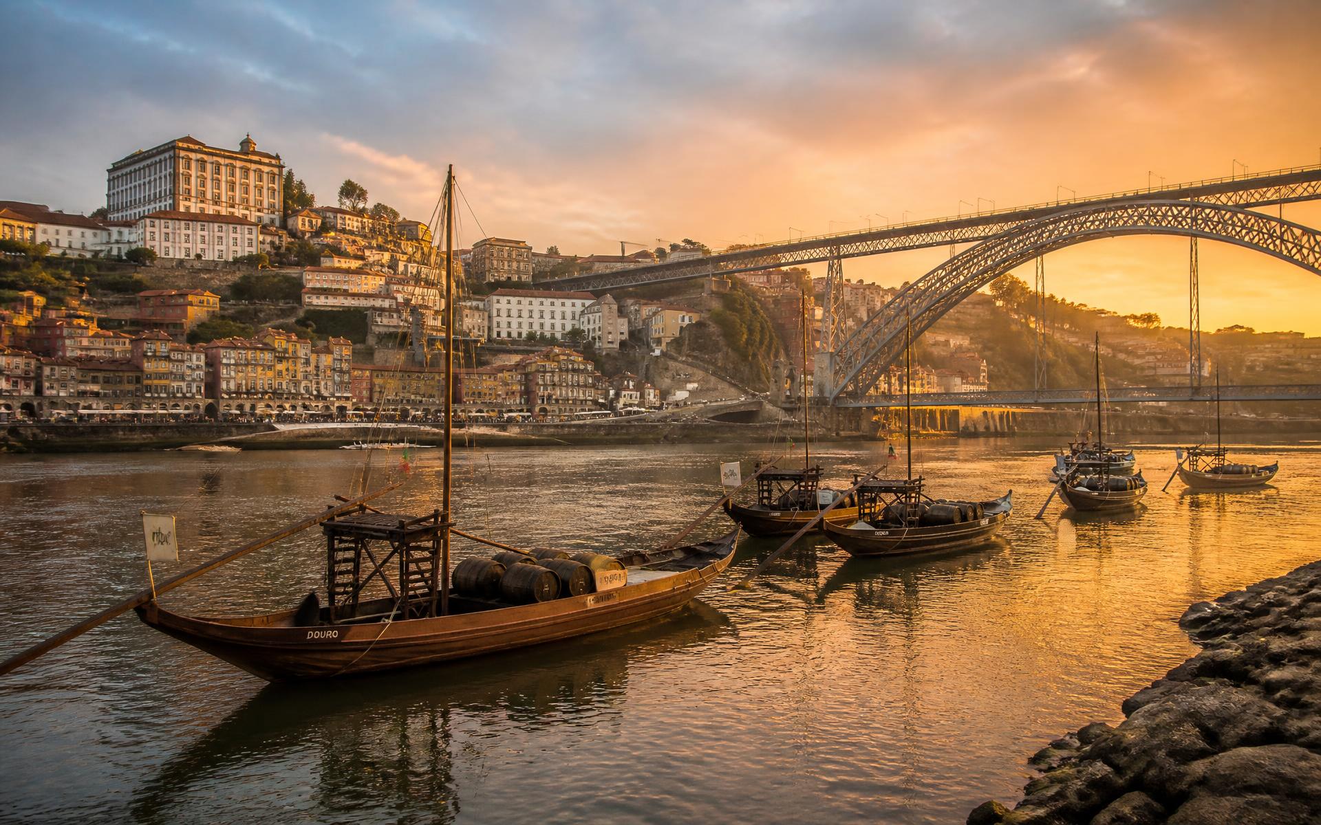 Ribeira do Porto ao pôr do sol com a ponte Dom Luís I e barcos rabelos no rio Douro